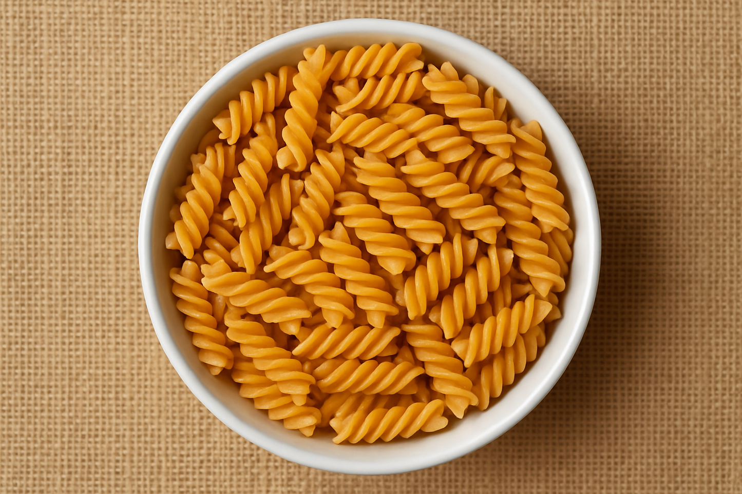Image 1800 x 1800 of a bowl of gluten free spiral pasta from above with a hessian background